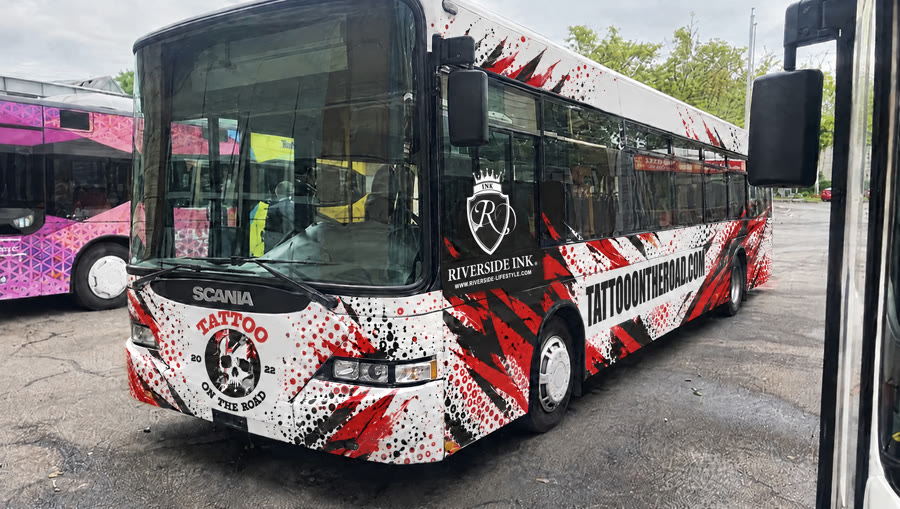 Der Tattoo-Bus von vorne: Totenkopf-Logo unter der Frontscheibe, Schriftzug tattooontheroad.com an der Seite.