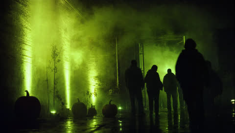 Nebel vor einer Industriehalle, von innen grün angeleuchtet.